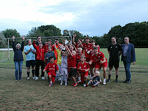 Eine Mannschaft in roten Trikots hebt jubelnd einen Pokal in die Höhe