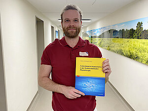 Mann hält ein Buch in den Händen